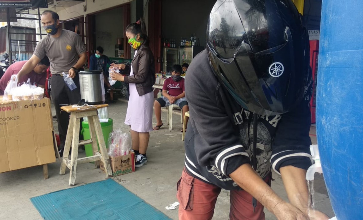 CUCI TANGAN | Salah satu warga mencuci tangan sebelum mengambil makanan dan minuman yang disediakan secara gratis. (Foto: Muji/SP)