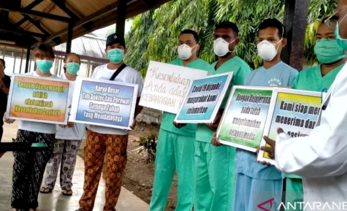 Tujuh orang pasien positif COVID-19 sembuh yang memegang spanduk berukuran kecil. Mereka dirawat di RSUD Jayapura dan dinyatakan sembuh dan telah dipulangkan pada Senin (20/4/2020) siang. (Foto: Antara/Musa Abubar)