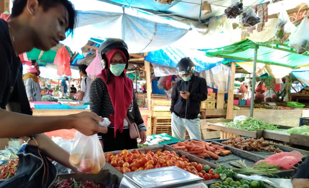 PASAR SENTRAL | Agung ketika melayani seorang pembeli di lapaknya di Pasar Sentral Timika. (Foto: Anya Fatma/SP)