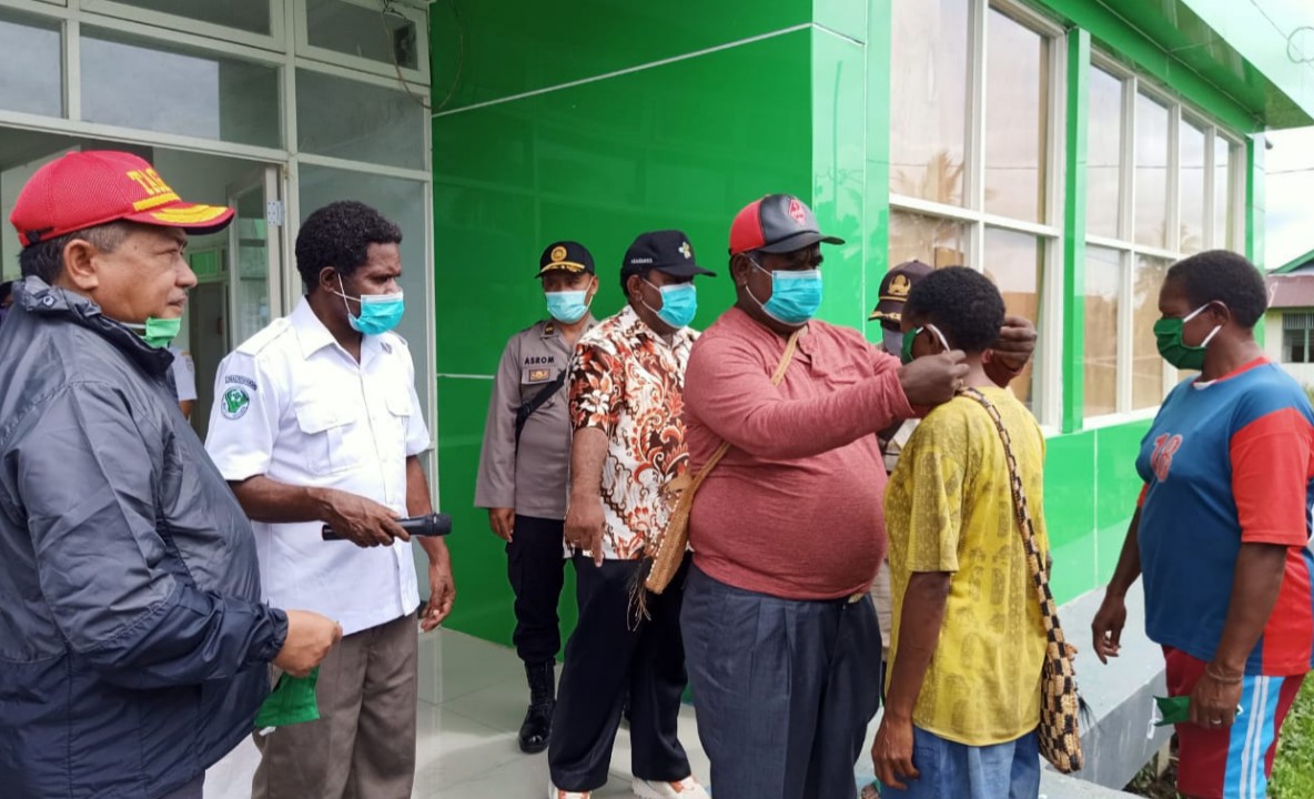 PAKAIKAN MASKER | Bupati Asmat Elisa Kambu ketika memakaikan masker kepada salah satu warga. (Foto: Humas Asmat/SP)