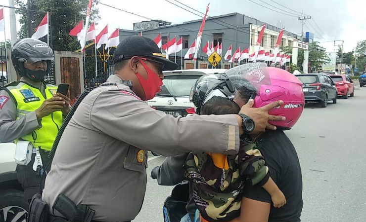 BAGI HELM | Kasatlantas Polres Mimika Iptu Devrizal memasangkan helm kepada penumpang ojek. (Foto: Muji/SP)