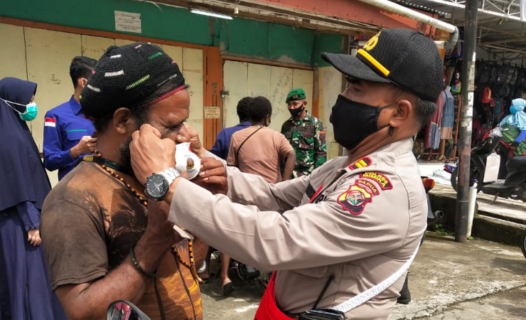 PAKAI - Iptu I Wayan Nurida saat memakaikan masker kepada salah satu warga. Foto: Muji/SP