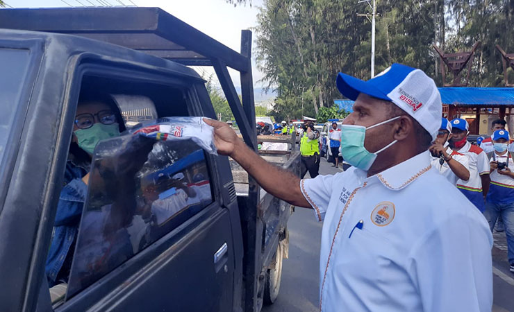 BAGIKAN | Ketua Harian PB PON Yunus Wonda saat memberikan souvernir kepada masyarakat pengguna kendaraan. (Foto: Vidi)