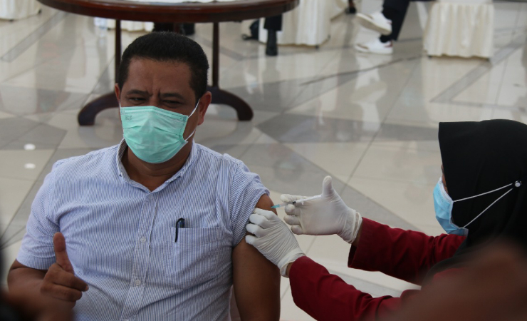 Bidan Rosdiana Ongan menancapkan jarum suntik vaksin Covid-19 ke lengan Kepala Dinas Kesehatan Mimika Reynold Rizal Ubra. (Foto: Sevianto Pakiding / SP)