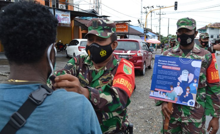 MASKER | Anggota Kodim 1710 Mimika saat memasangkan masker kepada warga yang tidak menggunakan masker. (Foto: Ist/SP)