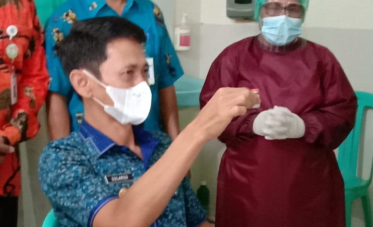 VAKSINASI | Wakil Bupati Merauke Sularso saat menunjukan vaksin Covid-19 sebelum disuntikan ke tubuhnya. Foto: M. Dul