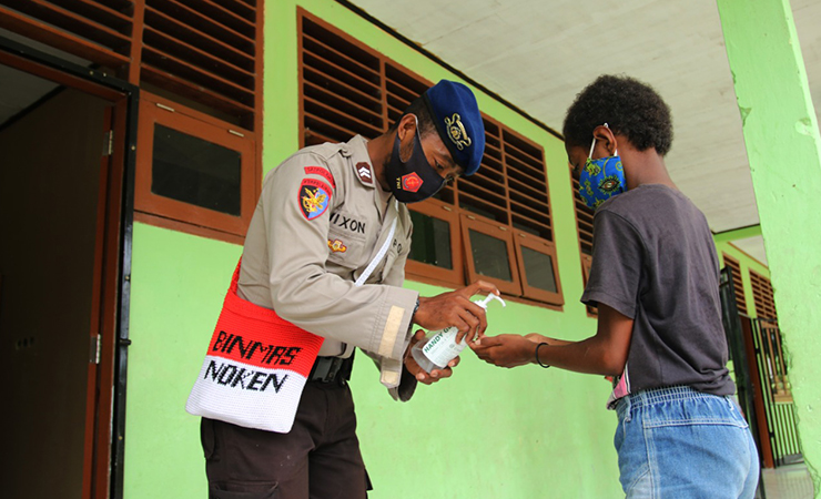 EDUKASI PROKES - Briptu Nixon, anggota Satgas Binmas Noken Polri memberikan hand sanitizer kepada seorang siswa sebelum aktivitas belajar mengajar di SD Inpres Kwamki Narama, Sabtu 20 Februari 2021. SEVIANTO PAKIDING / SEPUTARPAPUA