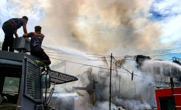 Personel Kepolisian Polres Mimika menembakan air dari truk water canon ke ruko yang terbakar di Jalan Yos Sudarso, Rabu (25/8/2021). (Foto: Yonri/Seputarpapua)