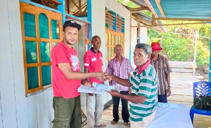 SERAHKAN | Masyarakat saat menyerahkan Hasil Terjemahan Alkitab Bahasa Saweru kepada Markus Imbiri (Topi hitam) di Kampung Umani - Serui Papua. (Foto: Ist)