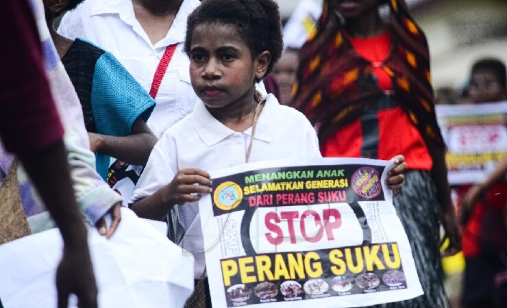 Seorang anak memegang pamflet menolak perang suku pada aksi damai di Timika, Papua, Selasa (19/10/2021). (Foto: Yonri Revolt/Seputarpapua)