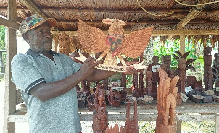 MENGUKIR | Timotius Samin merupakan salah satu Maramowe yang handal saat sedang bersantai sambil mengukir di samping rumahnya. (Foto: Kristin Rejang/Seputarpapua)