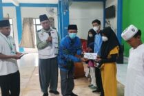 SERAHKAN | Kepala Disdukcapil menyerahkan bantuan dari BAZNAS Mimika kepada anak sekolah. (Foto: Mujiono/Seputarpapua)