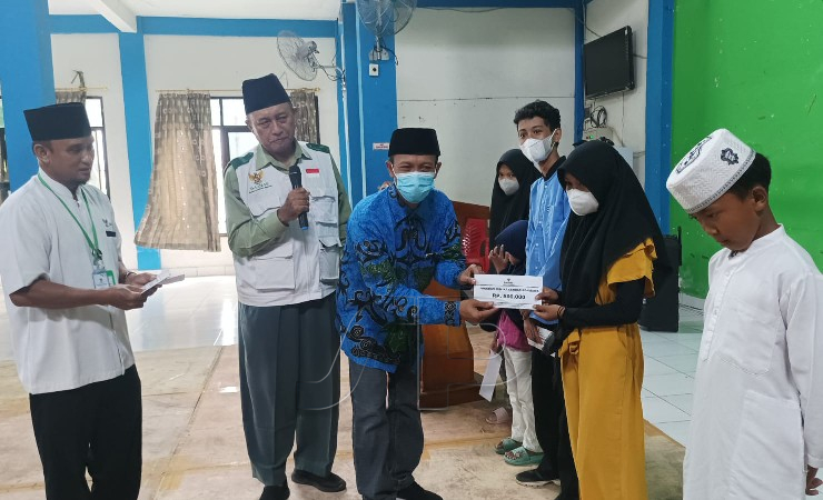 SERAHKAN | Kepala Disdukcapil menyerahkan bantuan dari BAZNAS Mimika kepada anak sekolah. (Foto: Mujiono/Seputarpapua)