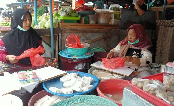 Mujianti (kanan) saat berada di lapak Tempe tahu miliknya di Pasar Sentral Timika. (Foto: Kristin Rejang/Seputarpapua)