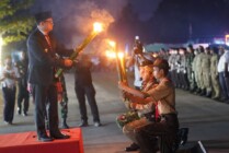 Pj Bupati Mappi Michael R. Gomar menyalakan obor kepada perwakilan peserta upacara Taptu