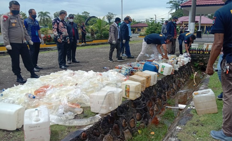 Foto 1: Proses pemusnahan barang bukti minuman beralkohol buatan lokal yang ditumpahkan ke dalam selokan. (Foto: Arifin/Seputarpapua)