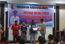 Pj Bupati Mappi Michael R. Gomar menyalurkan bantuan stimulan kepada pelaku usahan dan UMKM asli Papua. (Foto: Ist)