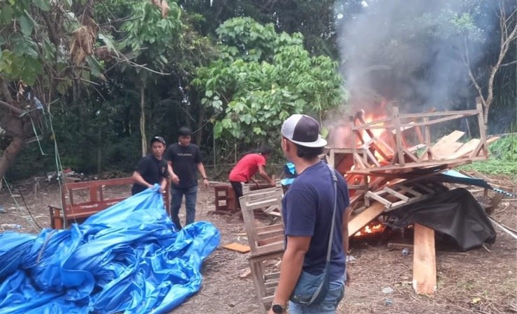 Petugas membakar kayu-kayu dan tenda yang digunakan membangun arena perjudian sabung ayam dan dadu di Kilo 10, Mimika, Papua Tengah. (Foto: Ist)