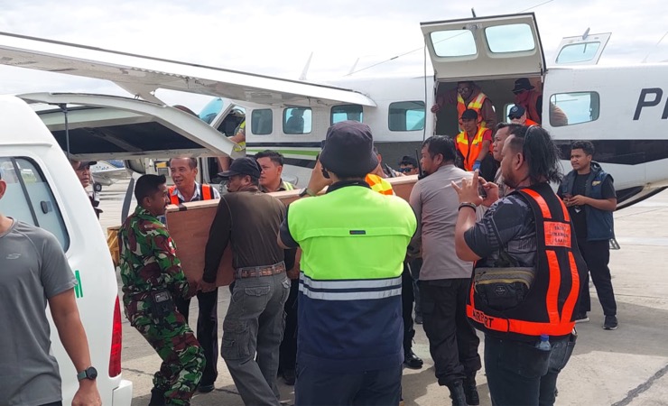 Personel TNI, Polri, petugas maskapai dan keluarga ketika memindahkan peti jenazah Damri dari pesawat ke mobil jenazah saat tiba di Bandara Mozes Kilangin Timika, Selasa (24/1/2023). (Foto: Ist)