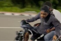 Seorang pemuda beraksi mengemudikan sepeda motor sambil memegang pisau mengancam pengendara lain di Jalan W.R Soepratman Timika, Mimika, Papua Tengah. (Foto: Tangkapan layar video viral)