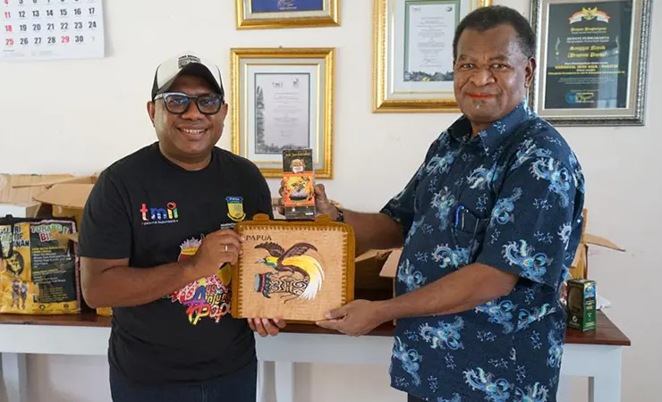 Kepala Dinas KLH Papua Jan Jap Ormuseray menyerahkan produk UMKM koperasi binaannya kepada Kepala Badan Penghubung Daerah Papua, Alexander Kapisa. (Foto: Dok Humas Pemprov Papua)