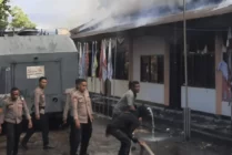 Suasana aparat kepolisian berupaya memadamkan api yang membakar Kantor KPU Kabupaten Jayaphra dan tiga kantor lainya. (Foto: Humas Polres Jayapura)