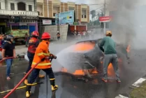 Petugas memadamkan api pada mobil sedan yang terbakar. (Foto: Tarmizi/ Seputarpapua)