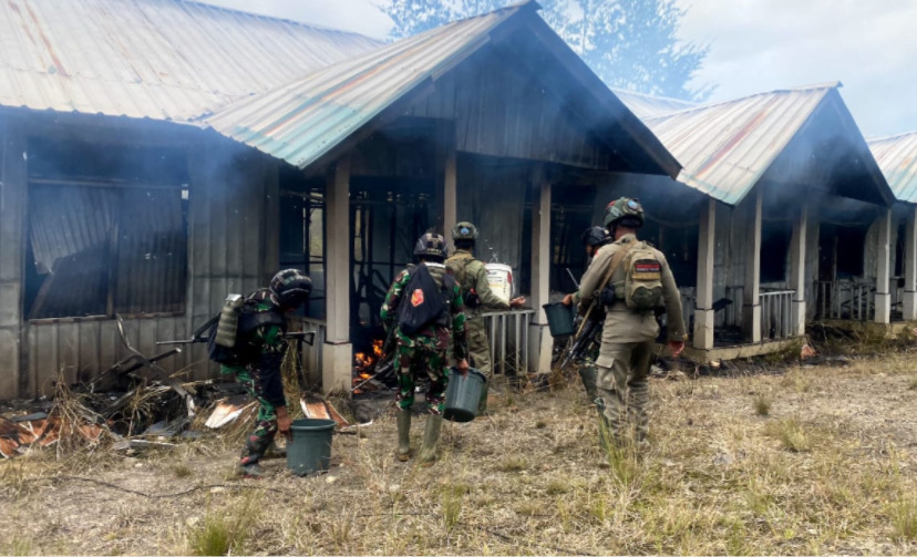 Aparat keamanan memadamkan api di perumahan Nakes yang dibakar KKB. (Foto: Ist)